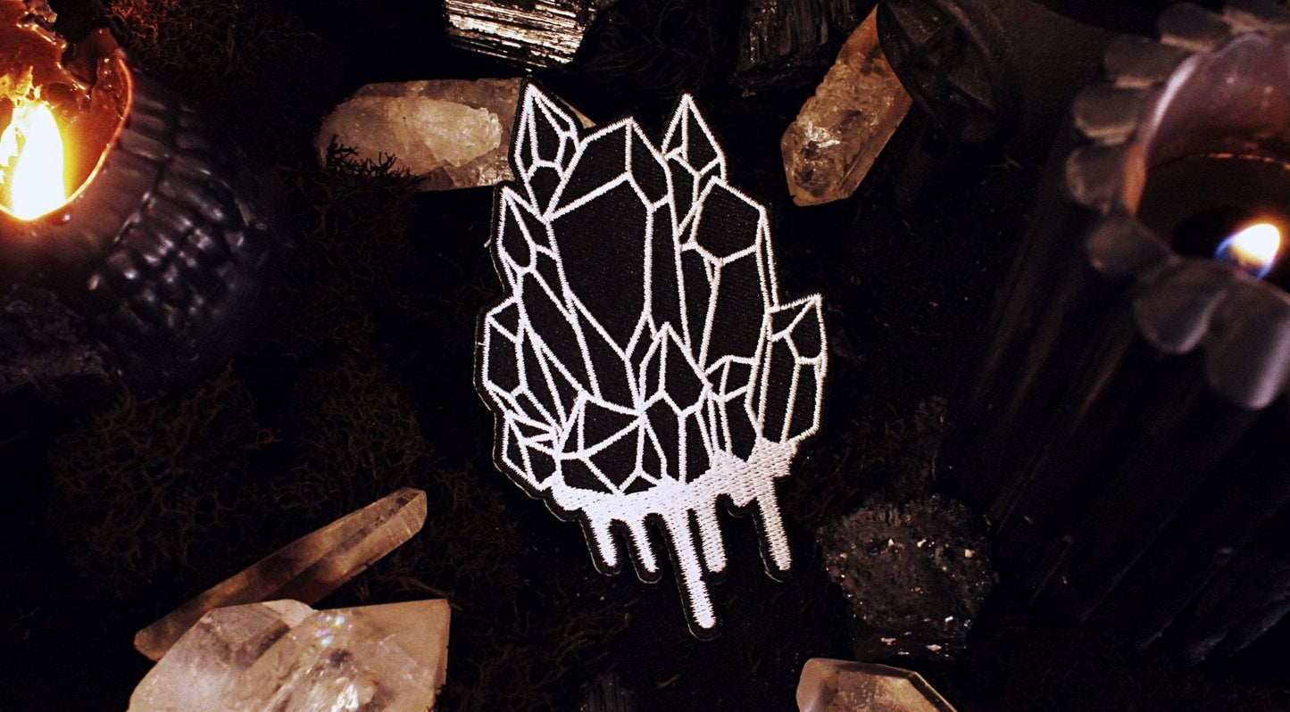 Iron on embroidered patch of a black crystal cluster with white outlines and dripping white at the bottom. Original design by GRRRL Spells.