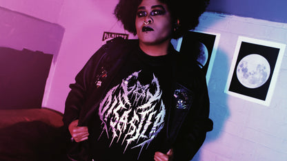 Gay Disaster Shirt - A person wearing a black t-shirt with the words "Gay Disaster" in a black metal style front printed on it in silver metallic ink. the A in "Gay" is shaped like an inverted pentagram. Original design by GRRRL Spells. 