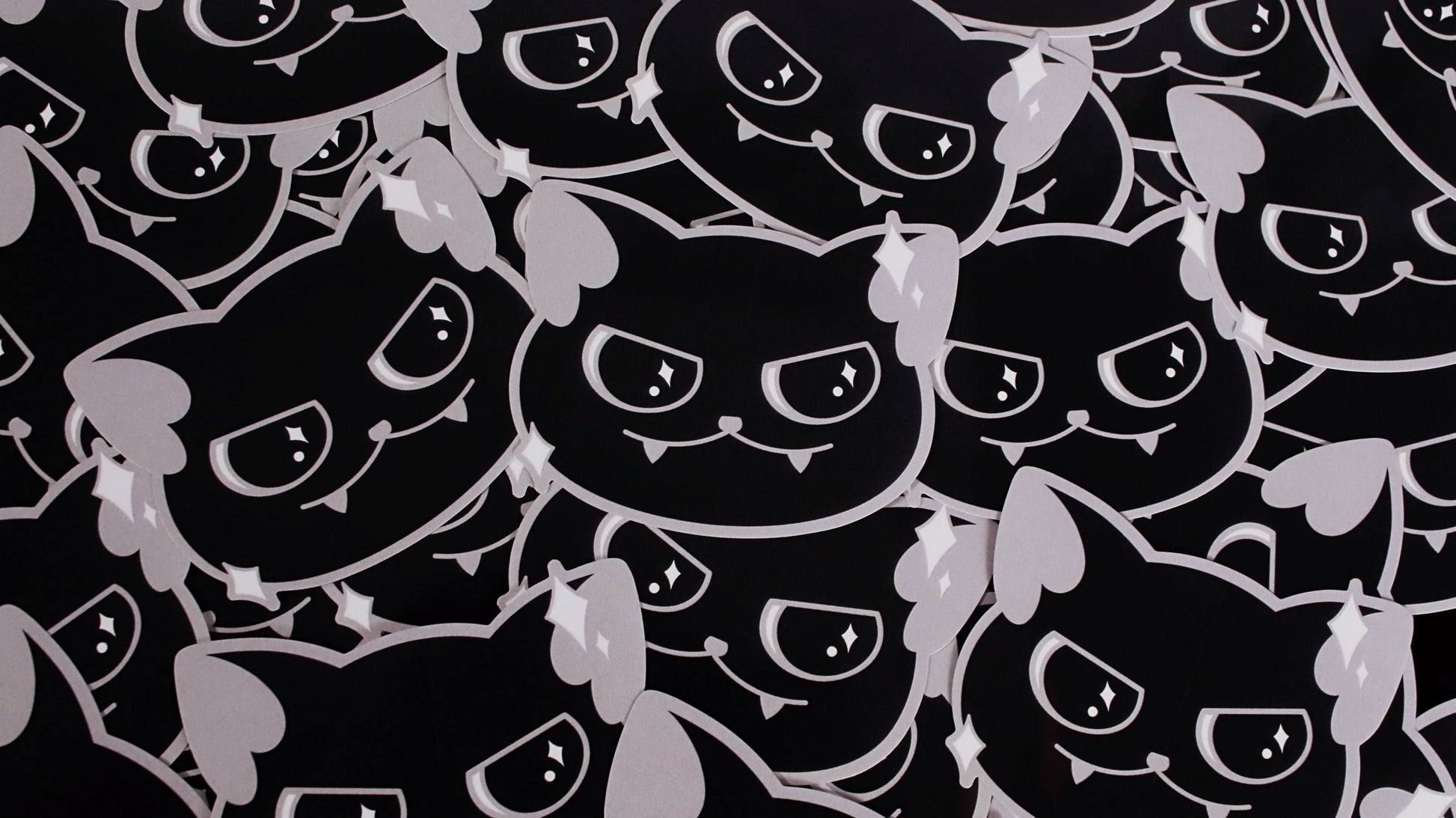 Vinyl stickers of a cute black cat with a little smirk and sparkles around its face. Original design by GRRRL Spells.