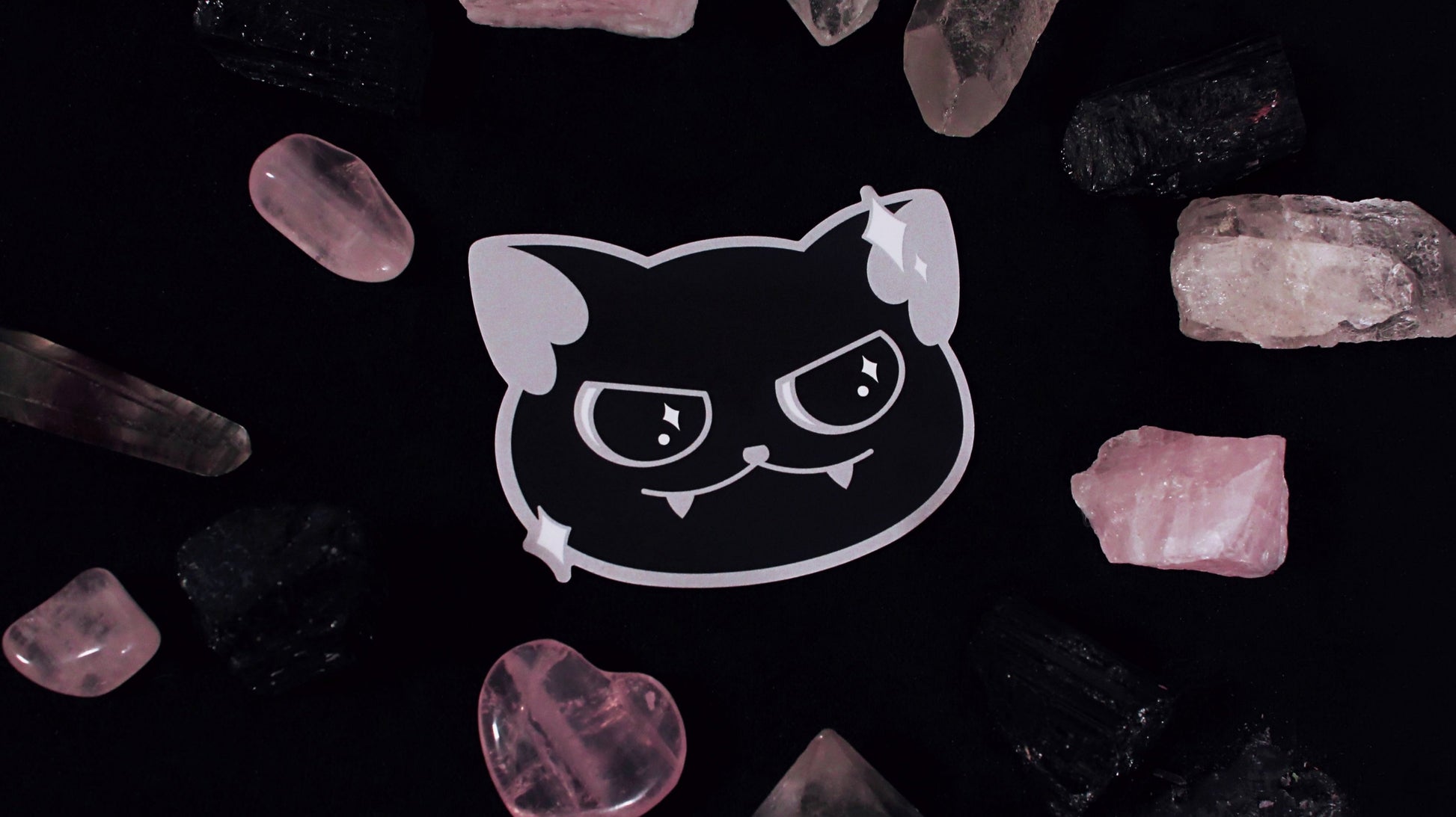 A vinyl sticker of a cute black cat with a little smirk and sparkles around its face. Original design by GRRRL Spells.