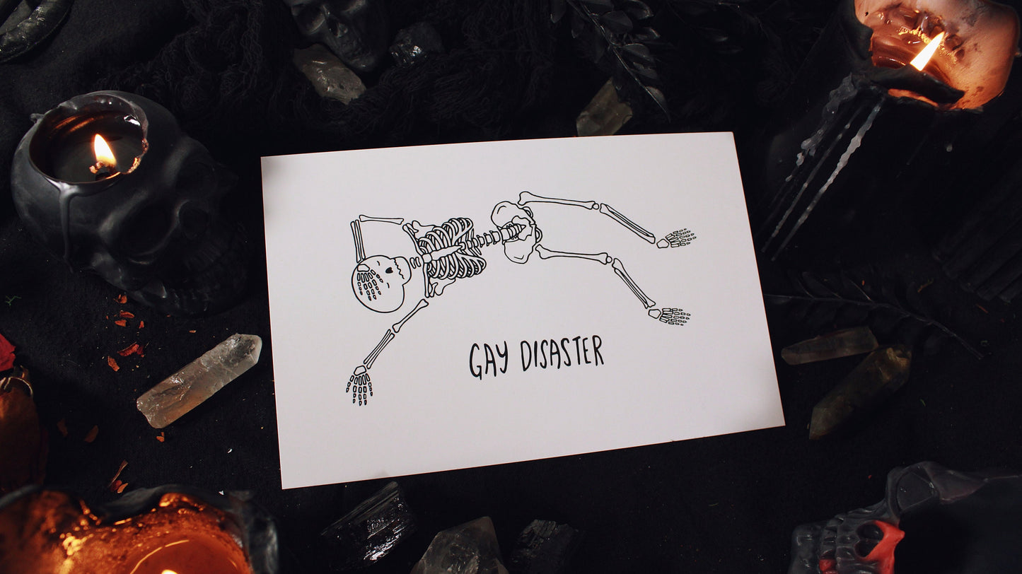 Gay Disaster Print - Illustration of a skeleton laying horizontally with one hand over their forehead and another hand splayed out on the side, on a white background with the words "Gay Disaster" at the bottom. Printed on 8.5" x 5.5" card stock. Original design by GRRRL Spells. 